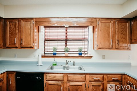 A kitchen with wooden cabinets and a black dishwasher.