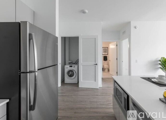 A modern kitchen with a black refrigerator and a washing machine in the background.