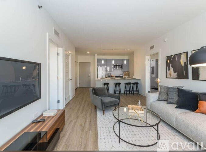 A modern living room with a grey sofa, a glass coffee table, and a television on the left side.