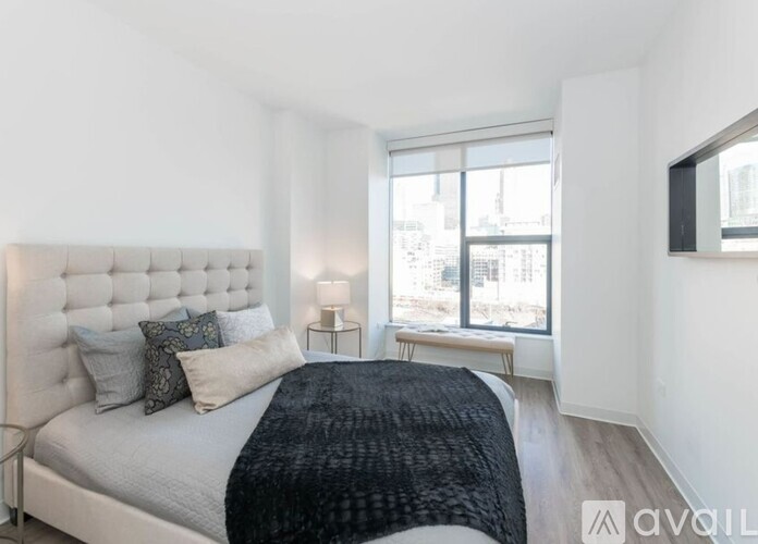A bedroom with a large bed and a window overlooking a cityscape.