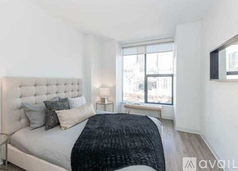 A bedroom with a large bed and a window overlooking a cityscape.