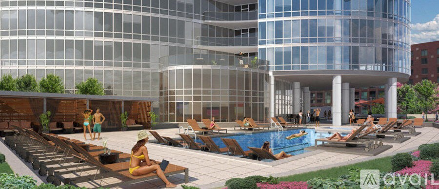 A modern building with a pool and lounge chairs.
