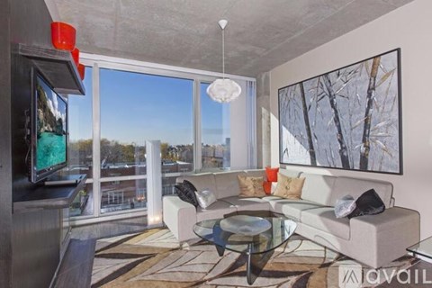 A modern living room with a glass table and a large window overlooking a cityscape.