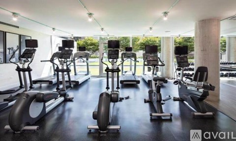 A gym with a row of stationary bikes and elliptical machines.