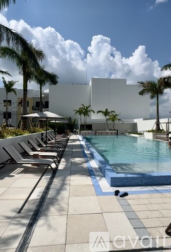 A pool area with sun loungers and a white building in the background.