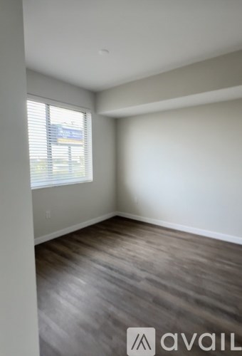 A room with wooden flooring and a window with blinds.