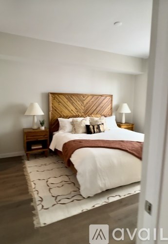 A bedroom with a large bed and two lamps on either side of the bed.