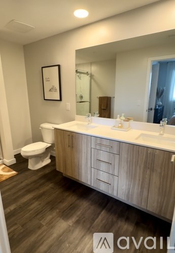 A bathroom with a toilet, sink, and wooden cabinets.