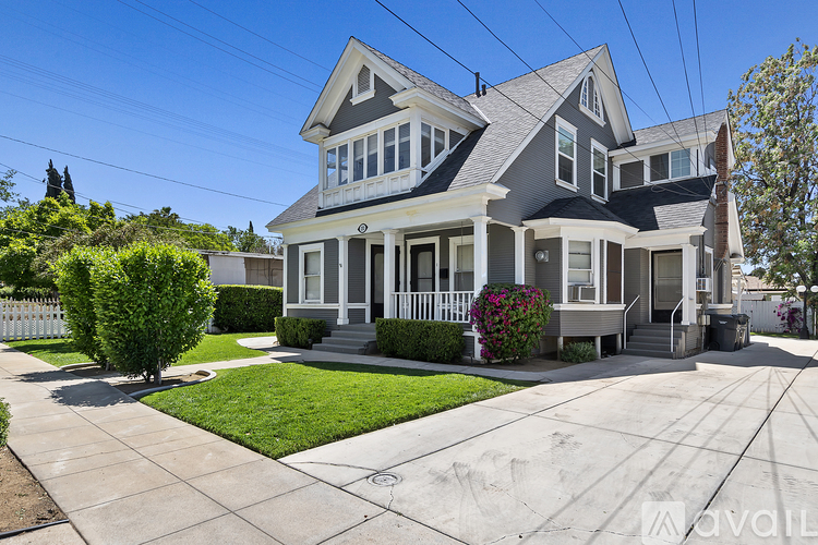A two-story house with a front yard and a white picket fence.