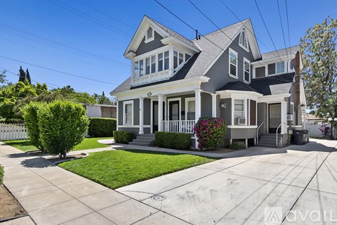 A two-story house with a front yard and a white picket fence.