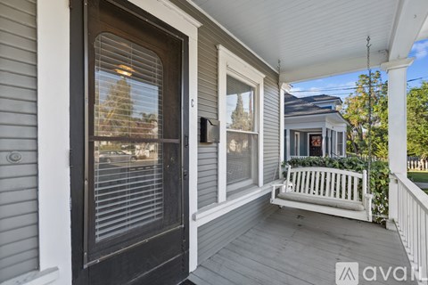 A porch with a bench and a door with a window.