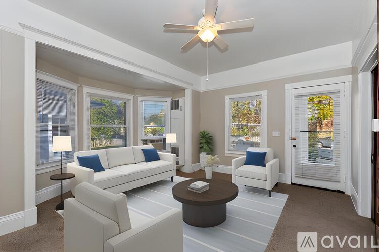 A living room with a white couch, a brown coffee table, and a ceiling fan.