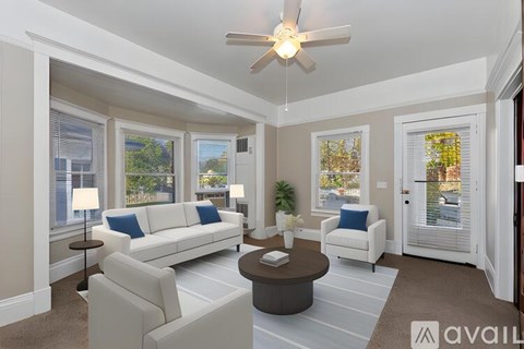A living room with a white couch, a brown coffee table, and a ceiling fan.