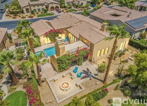 A house with a pool surrounded by palm trees and a patio area.