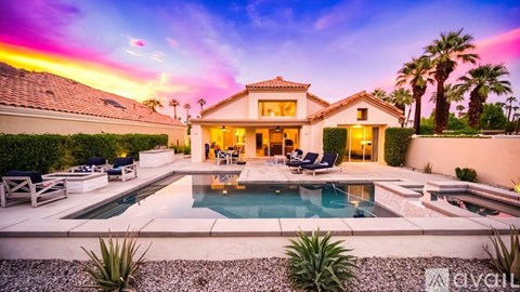 A house with a pool in the foreground and palm trees in the background.