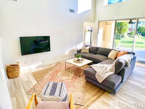 A living room with a grey couch and a flat screen TV mounted on the wall.