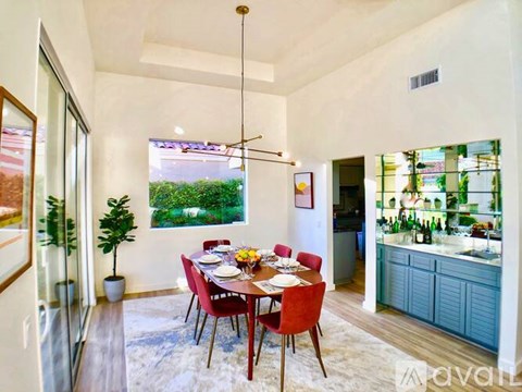 A dining room with a table set for six with a view of a backyard.