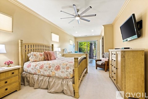 A bedroom with a large bed and a television mounted on the wall.