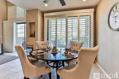 A dining room with a table set for four and a clock on the wall.