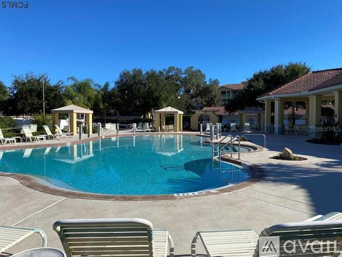 A pool with a blue tinted water and sunbeds around it.