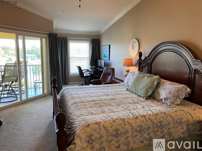A bedroom with a large bed and a balcony with chairs.