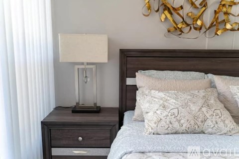 A bedroom with a bed, nightstand with a lamp, and a wall decoration.