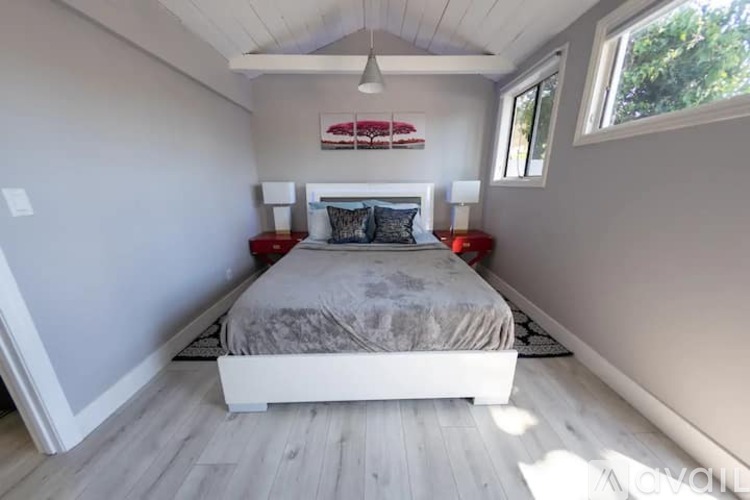 A bedroom with a bed, two lamps, and a painting on the wall.
