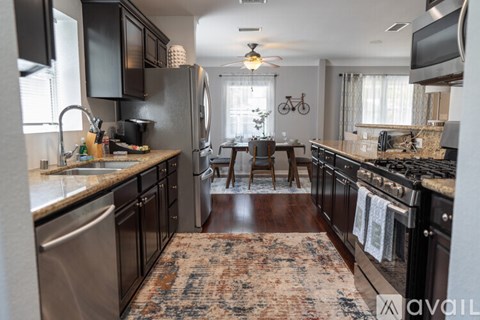 A kitchen with black cabinets and a rug on the floor.