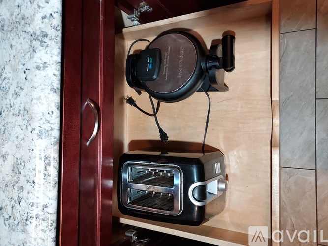 A toaster oven is placed on a drawer with a pair of headphones hanging on the handle.