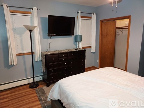 A bedroom with a bed, dresser, and television.