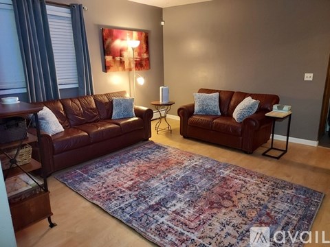 A living room with brown leather couches and a large rug.
