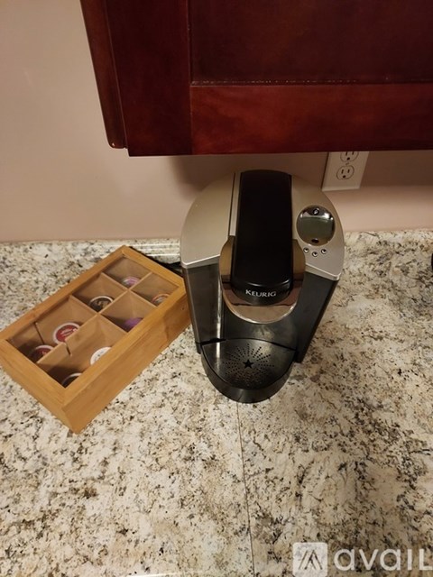 A black and silver shoe horn with a wooden box of shoe trees in the background.