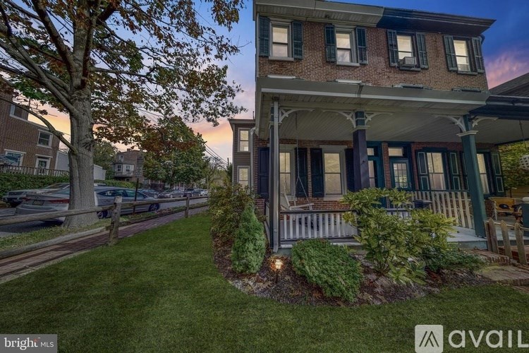 A house with a porch and a tree in front of it.