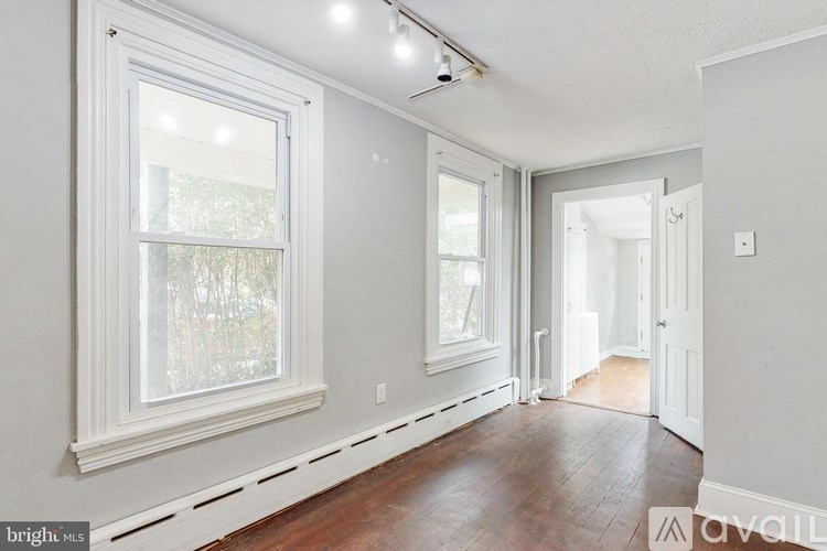 A bright, empty room with a window and wooden floors.