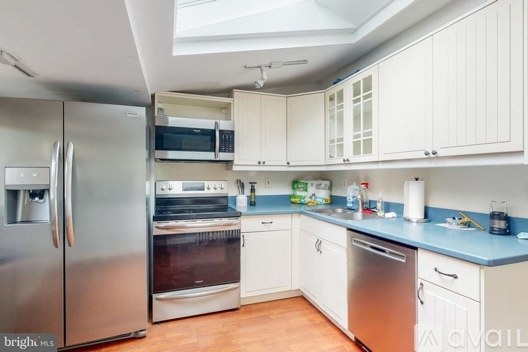 A kitchen with white cabinets and a stainless steel refrigerator.