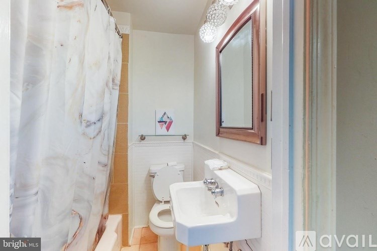 A bathroom with a toilet, sink, and mirror.