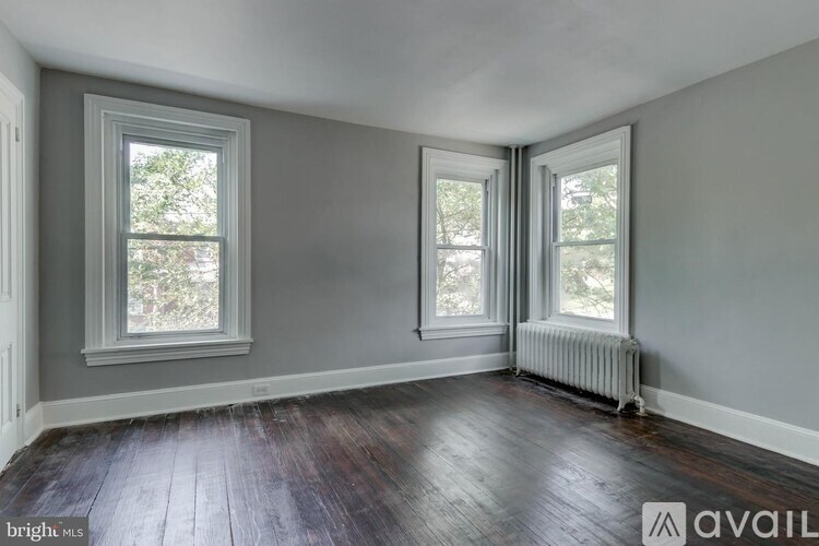 A room with two windows and a radiator on the wall.