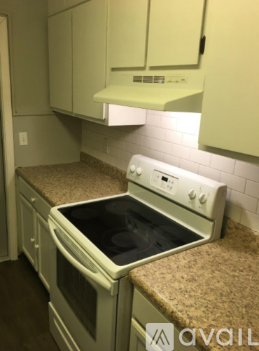 A white oven with a black stove top is in a kitchen with white cabinets.