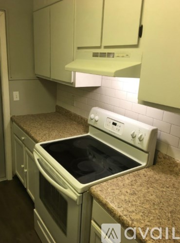 A white oven with a black stove top is in a kitchen with white cabinets.