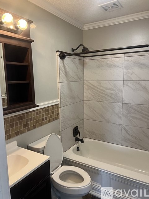 A white toilet is in a bathroom with a marble wall.