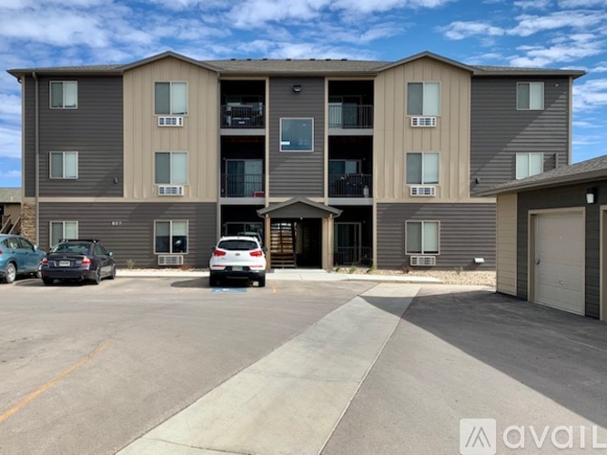 A multi-story apartment building with cars parked in front.