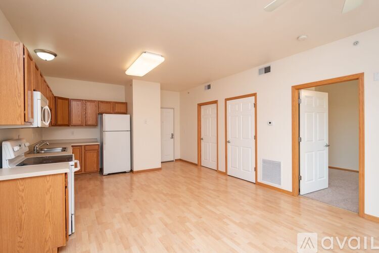 A kitchen with wooden cabinets and a white refrigerator is available for rent.