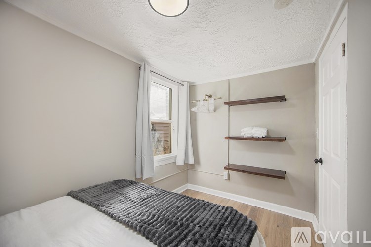A bedroom with a bed, window, and shelves.