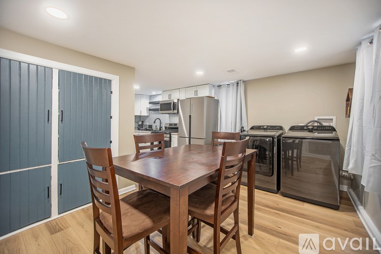A kitchen with a table and chairs in the foreground and a refrigerator and oven in the background.