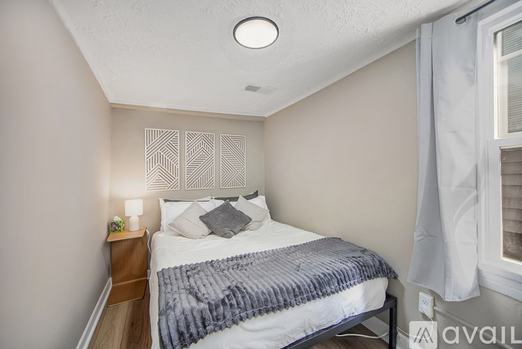 A bedroom with a bed, nightstand, and window.