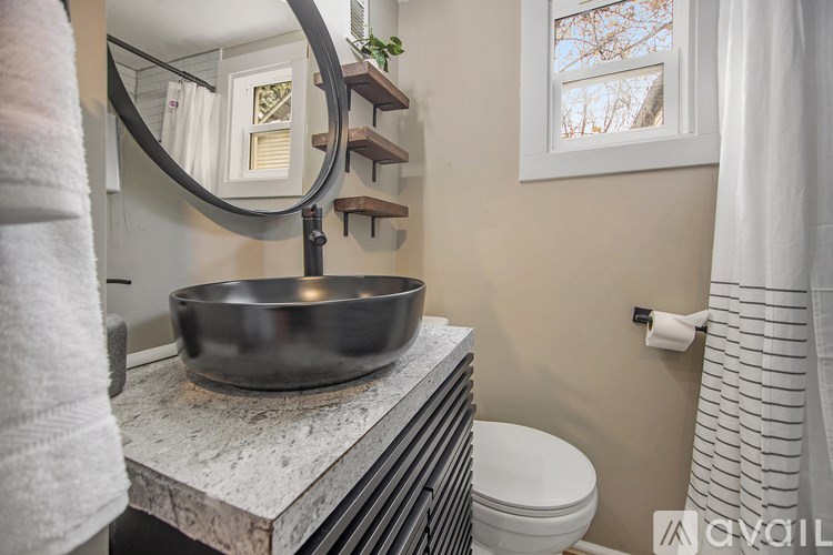 A bathroom with a round mirror, a bowl on the counter, and a towel hanging on the wall.