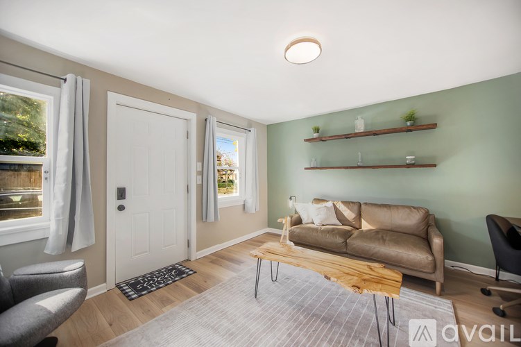 A living room with a couch, chair, and a window with curtains.