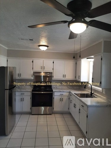 A kitchen with a refrigerator, sink, and cabinets.