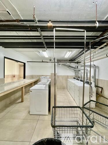 A shopping cart is in the foreground of an industrial laundry room.