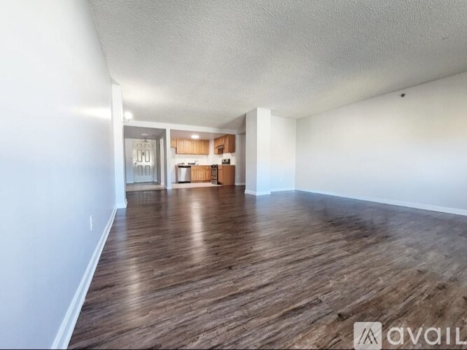 A spacious room with wooden flooring and white walls.